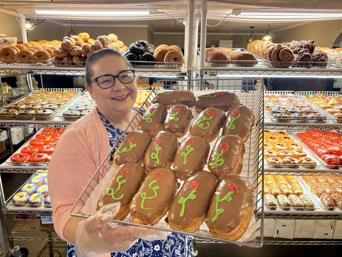 Jason’s Donuts team member smiling with a tray of chocolate donuts